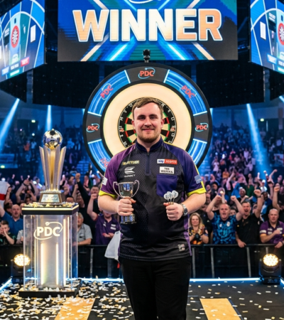 Luke Littler playing darts on stage during a professional tournament with fans watching