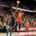 Indiana Fever and Connecticut Sun players competing during an exciting WNBA game with a packed arena crowd